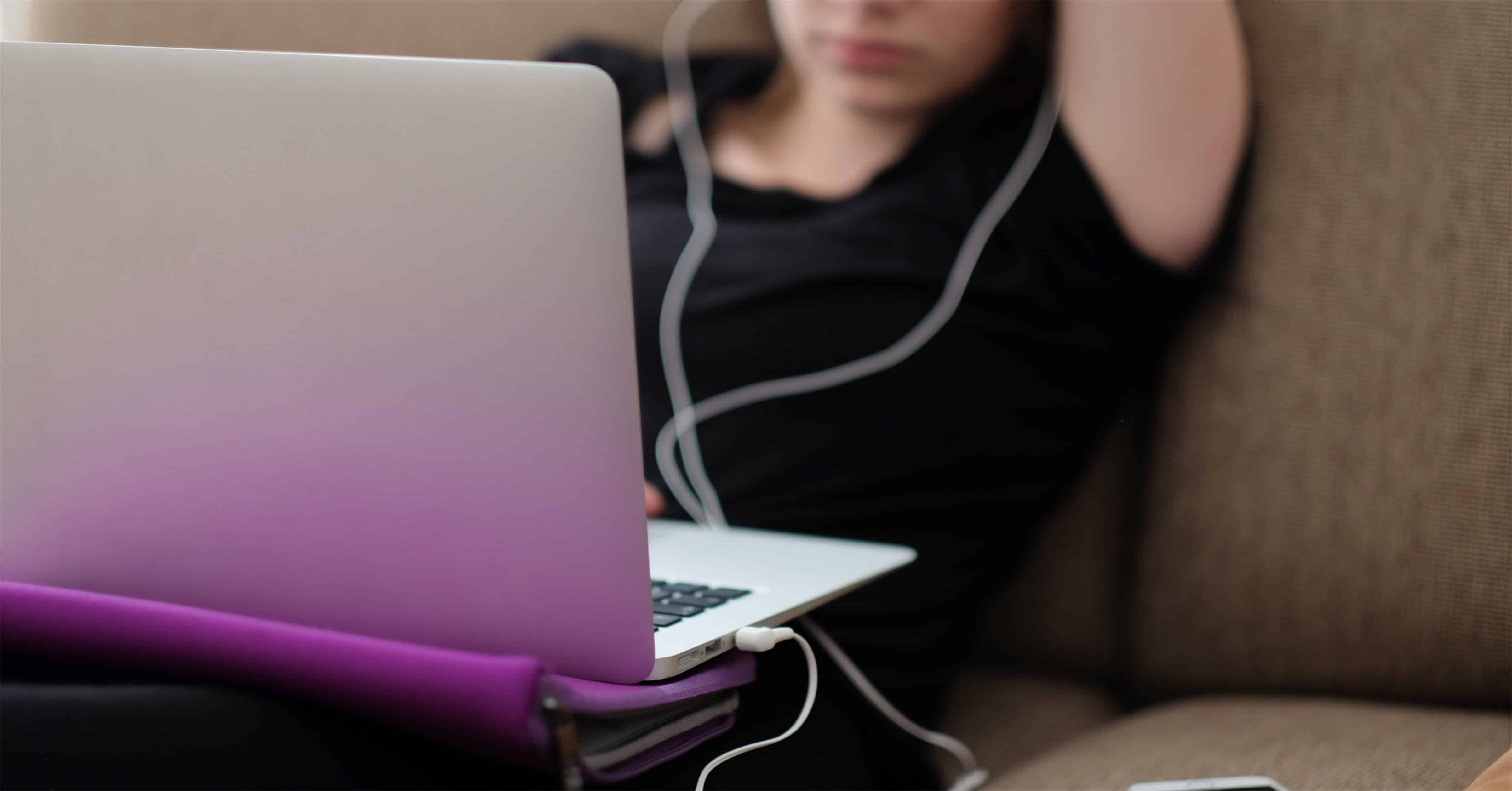 Woman on couch with laptop and headphones